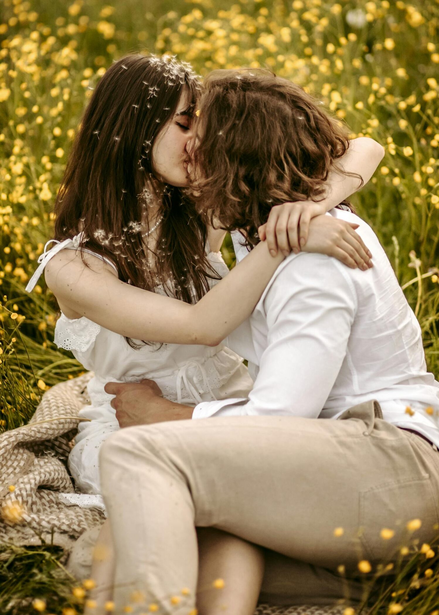 A couple sharing an intimate moment in a vibrant yellow wildflower meadow.