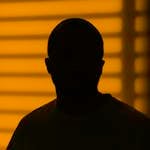 Dark silhouette of a man framed by yellow blinds creating a dramatic effect.